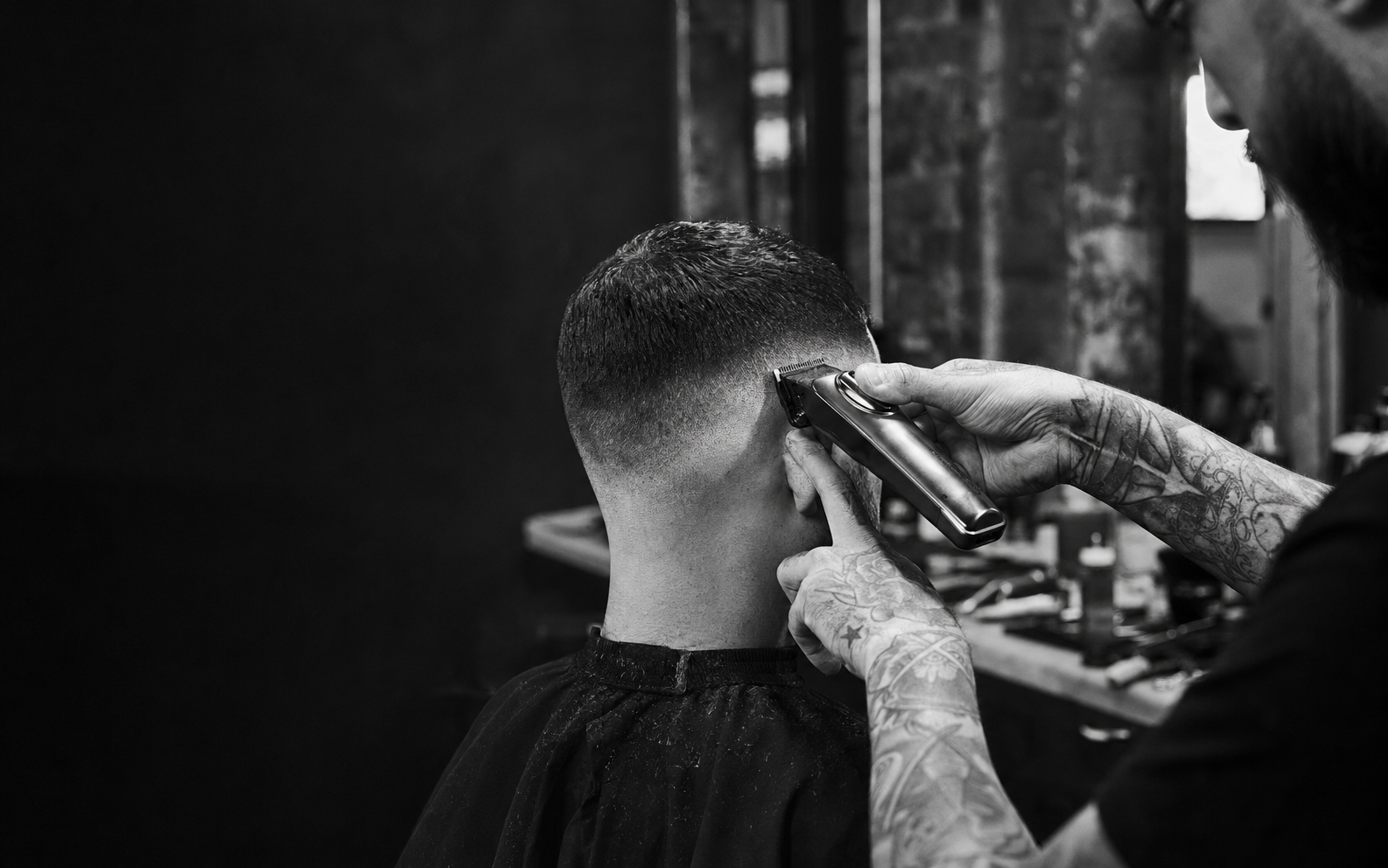 Barber shaping a precise fade with professional clippers